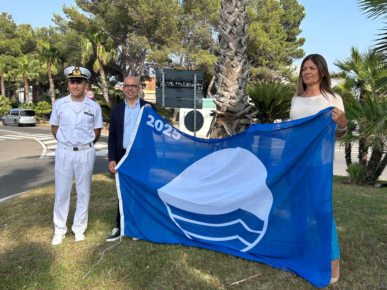 Il Sindaco Sanna, l'Assessore Zedda e il Comandante Chirizzi con la bandiera blu 2025